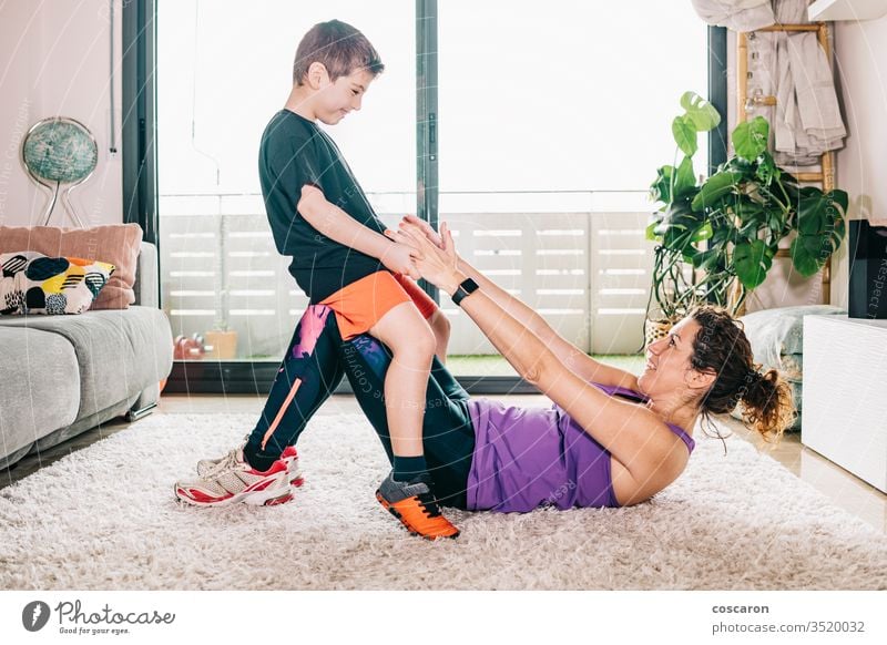 Little boy helping his mother to exercise active activity adult beautiful care caucasian child childhood coronavirus covid-19 energy family female fitness