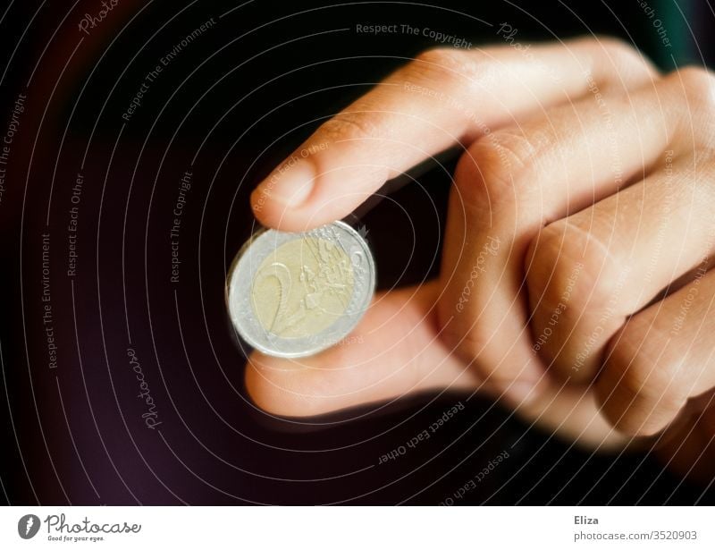 One hand holds a two euro coin between two fingers Euro euromint Coin Loose change Money finance gratuity Paying Black conceit Save Give Financial Industry