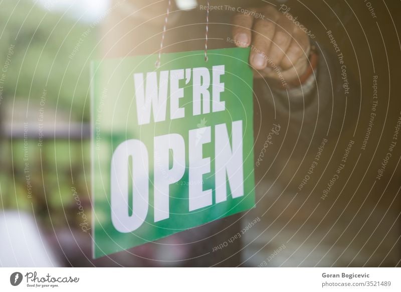 Business owner hanging an open sign at a glass door advertising banner bar board business busy cafe city concept day entrance exterior front hours information
