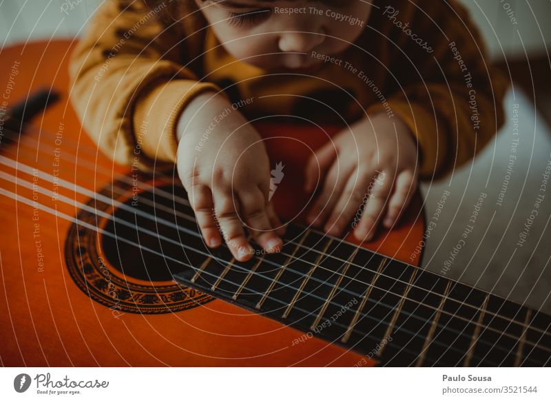 Child playing guitar Playing Happiness Caucasian indoor Curiosity Innocent Girl Home Looking cosy Joy Lifestyle Cute Infancy Happy learn Horizontal Beautiful