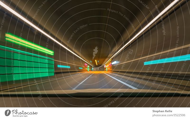 Fast moving with my car through a tunnel with leading lines and lights and blur effect. Abstract alcohol artificial light asphalt automobile blurred colors dark