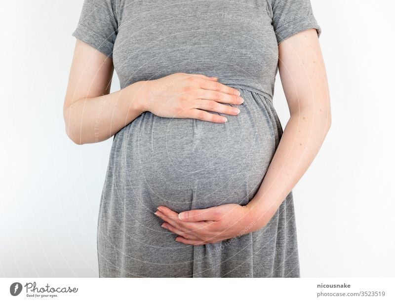 Pregnant woman who cares for her baby and shares love with him by touching her belly with her hands mama parental Embrace Child Caress Healthy Love tenderness