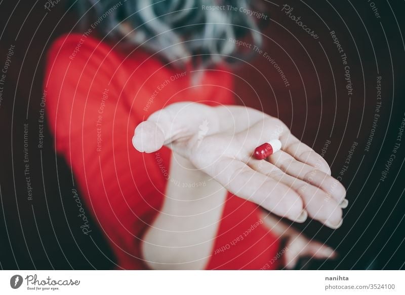 Young woman's hand holding a white and red pill drug medicine virus addict addictive addiction painkiller pain killers close up bokeh closeup blur focus macro