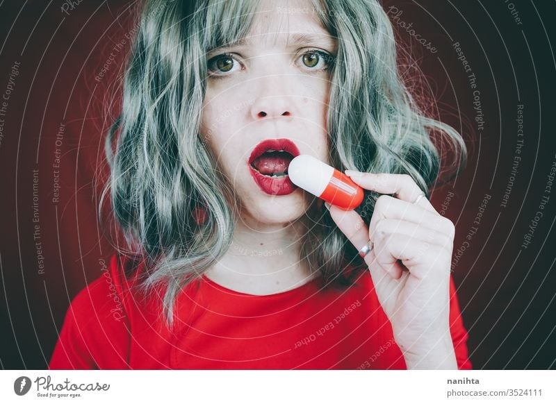 Young woman holding a giant pill in her hands medical medicine drug addict addiction concept distrust mistrust idea conceptual design red white portrait