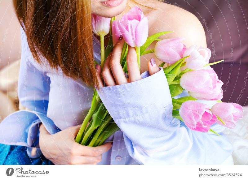 Closeup of woman's hands holding bouquet of pink tulips pj shirt blue innocence shoulder portrait tone image morning present red romantic caucasian cheerful