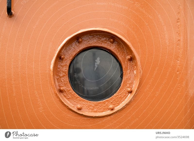 Detail of an orange ship's cabin with porthole in the middle Porthole reflection Orange Canceled Window Round close up mirrored