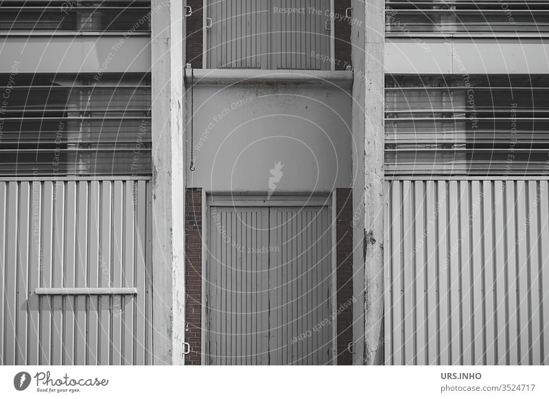grey facade of a warehouse Warehouse Facade Architecture Factory built Industrial plant door Stripe Window Storage shed store Gray symmetric Symmetry