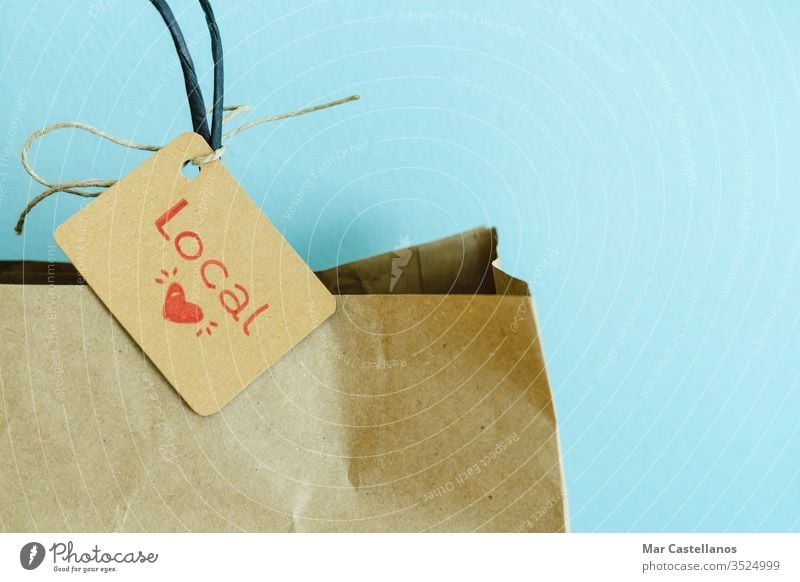 Paper shopping bag on a blue background. Label with heart and text LOCAL. Shopping concept. paper label recyclable sales local trade cardboard reusable