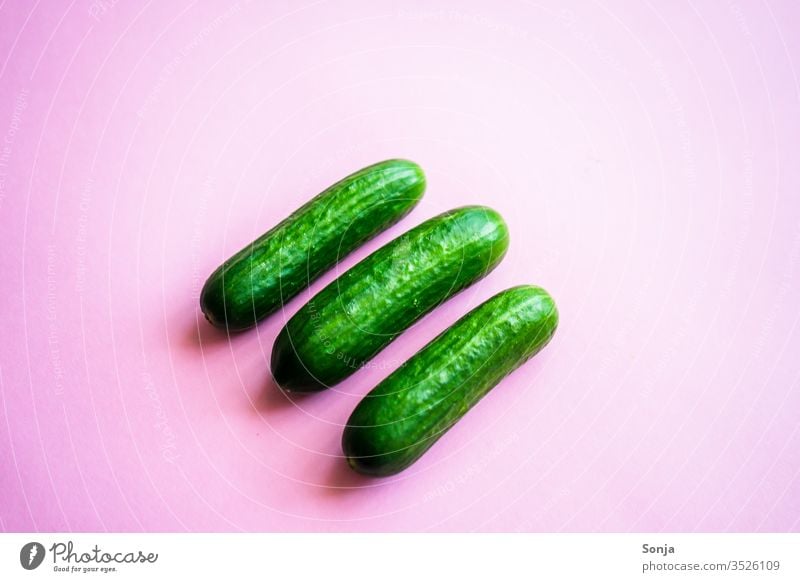 Three small green snack cucumbers on a pink background, top view Cucumber Small Vegetable Food Nutrition Healthy Fresh Vegan diet Colour photo Healthy Eating