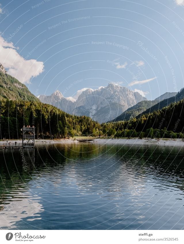 Lake surrounded by mountains in summer Mountain range Destination Far-off places Lakeside Summer Trip Calm Rock Freedom Hiking Relaxation Clouds Tourism