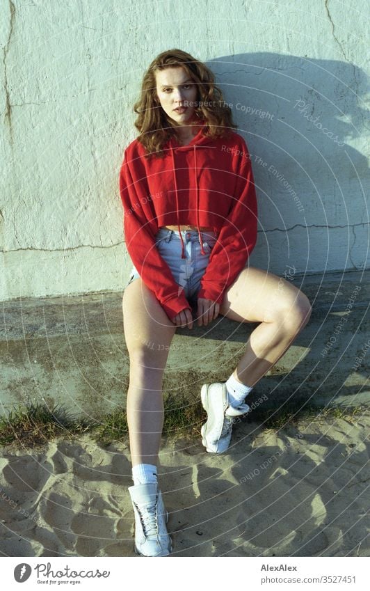 analogue portrait of a young woman with red hoodie and hot pants Woman girl already great Athletic Slim fit brunette Red Hot pants Curl long hair sneakers Legs