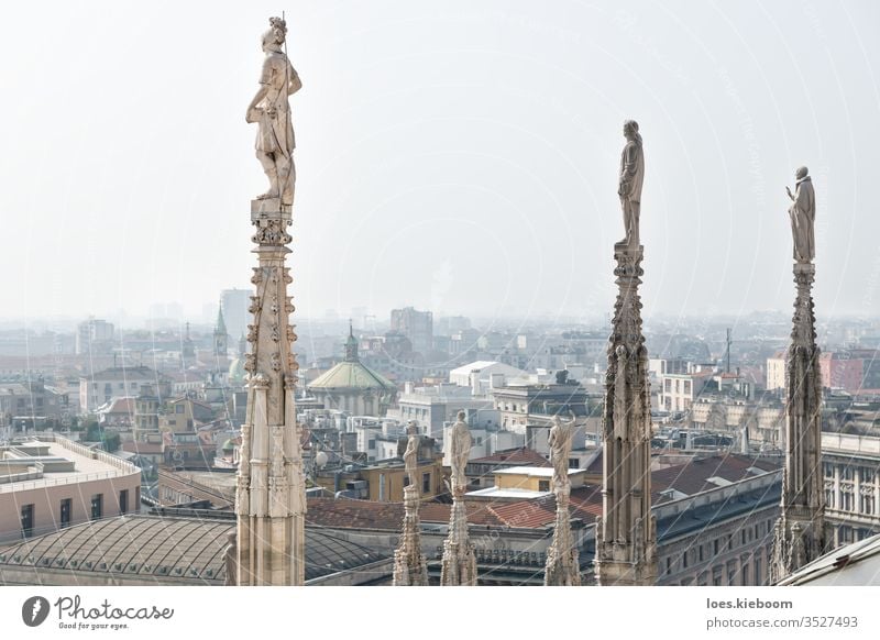 Statues of the dome looking over the cityscape of Milan, Italy on a sunny day cathedral italy architecture milan aerial panoramic view urban skyline landmark