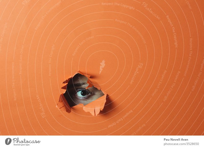 Eye looking through the hole. Abstract background eye woman orange abstract isolated paper copy space bright color colorful natural silence orange background