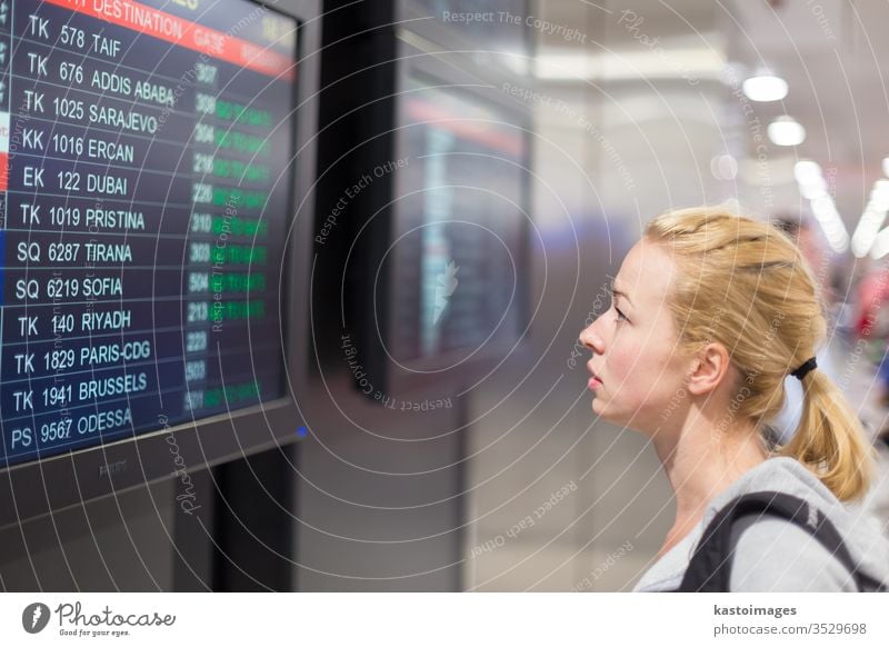 Passenger looking at flight information board. airport timetable display travel schedule woman young destination departure tourist baggage traveler girl luggage