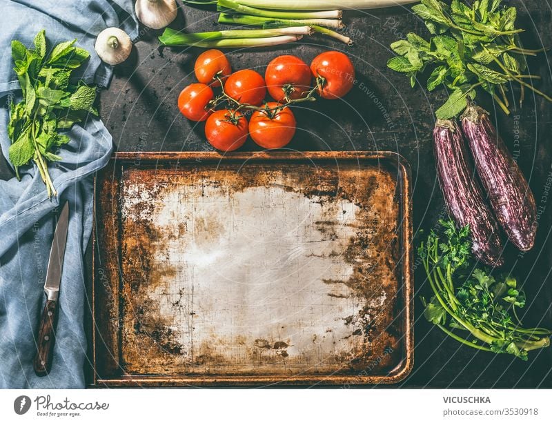 Cooking of vegetarian dish with tomatoes, eggplants, parsley, mint onions and garlic cooking rustic background vintage baking sheet place design board