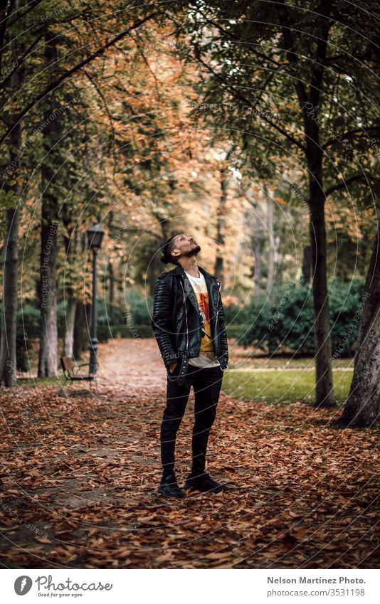 Portrait of a man wearing a leather jacket, at the park in autumn. portrait forest black trees autumn leaves hispanic Nature Day Exterior shot Colour photo