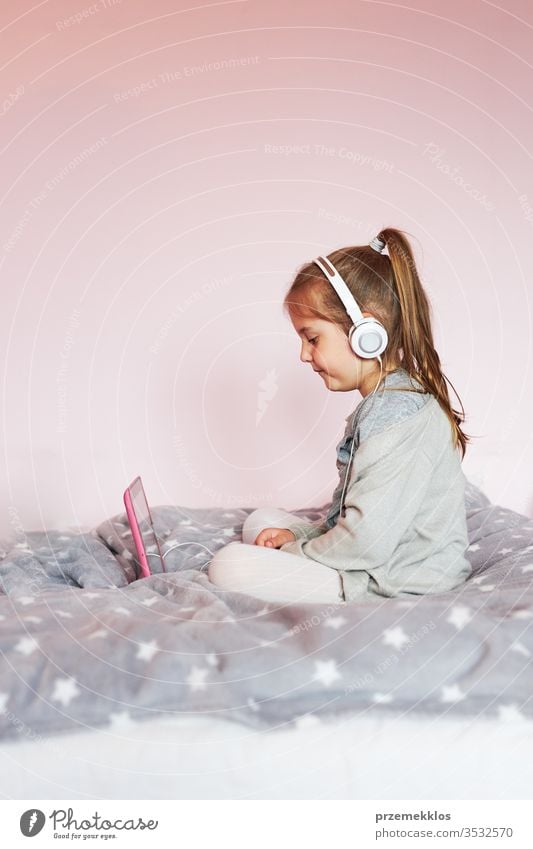 Little pre-school girl learns to solve puzzles online and plays educational games on tablet at home Child watching Listening Study instructively Puzzle Bed