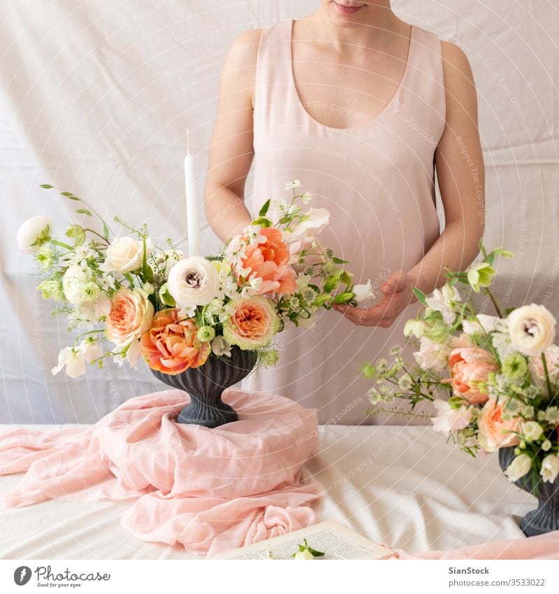 Woman hands touching  a bouquet of flowers. table woman young caucasian hold holding dress white vase candles soft light decoration background interior wedding