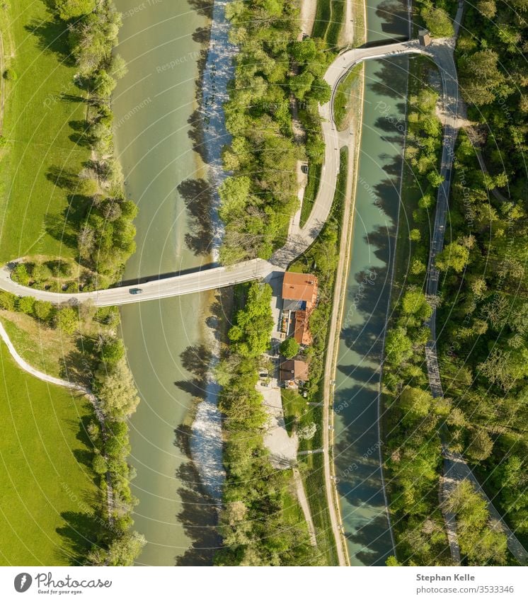 Top view from a drone at a driving car at a bridge over a river with a neaby forest and a house aerial view nature spring water green tree countryside summer