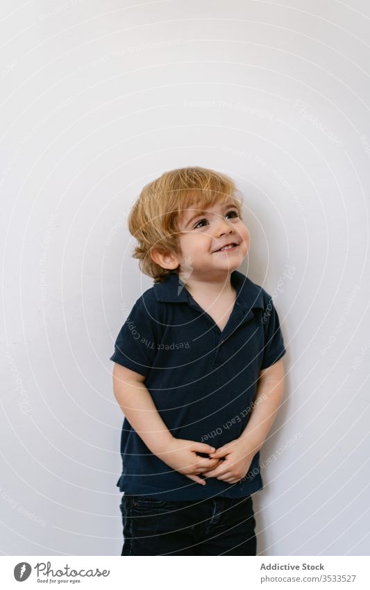 Happy little kid standing in a while wall happy boy energy preschool adorable child joy laugh fun childhood expressive playful smile home cute activity