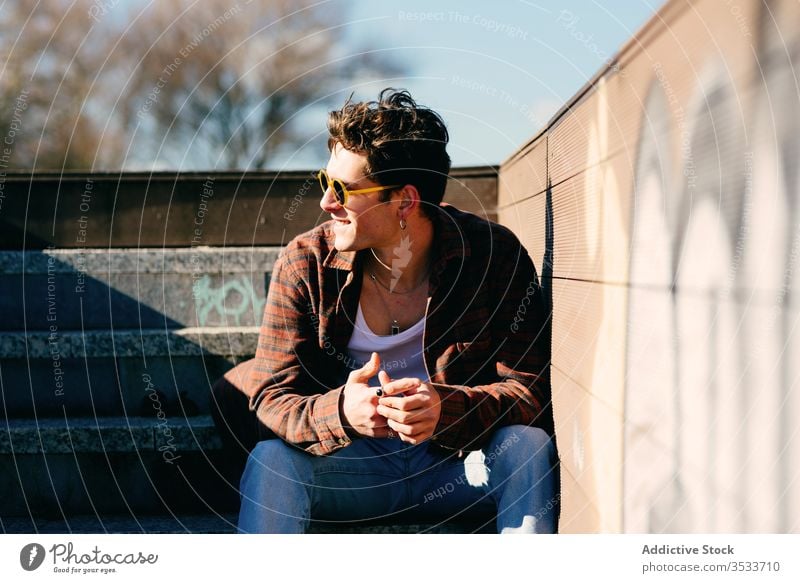 Young man resting on steps sit street urban city modern hipster male young sunny style casual millennial trendy town lifestyle relax staircase building guy