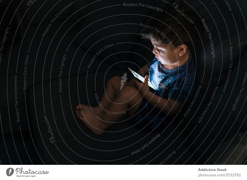 Curious little boy browsing smartphone at home child education application homework gadget communication connection technology room childhood kid sitting