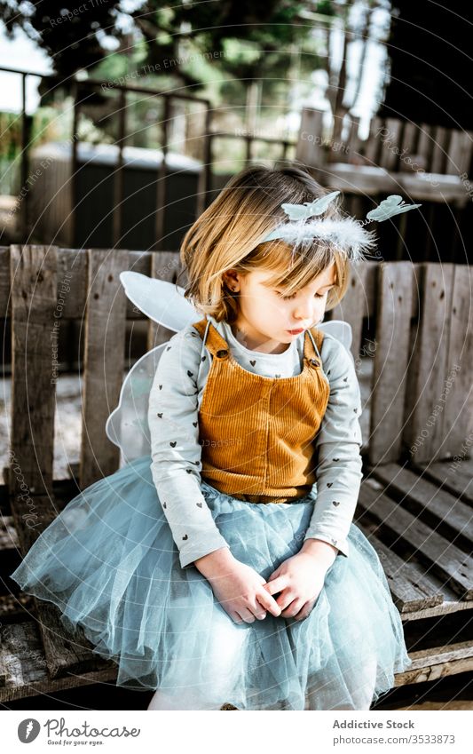 Little fairy sitting in yard girl costume bench shabby cute little play adorable child kid park childhood garden weathered masquerade relax seat rest magic