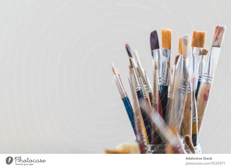 Many paintbrushes in glass on table set art colorful hobby workshop studio gallery equipment modern design creative workplace workspace material instrument