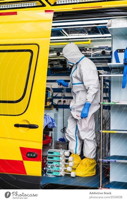 Doctor in protective suit standing in ambulance car doctor door equipment patient virus infection examine uniform inspect hospital service vehicle safety