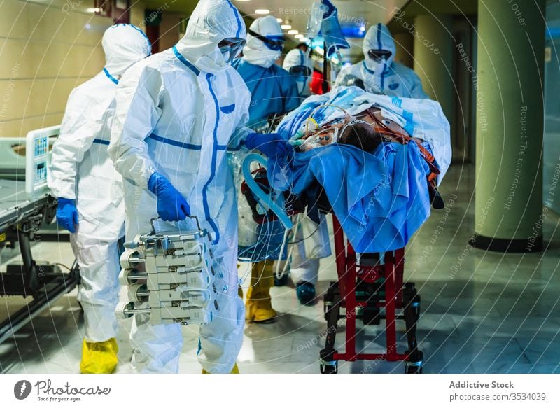 Group of doctors transporting patient to operating room group hospital viral infection hall clinic uniform mask specialist equipment health care medicine
