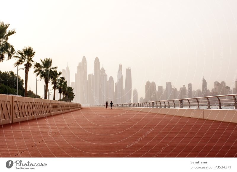 Morning run, a man and a woman run along the road with a beautiful view of Dubai. UAE breakwater stones sea beach blue sky landscape tourism coast nature ocean