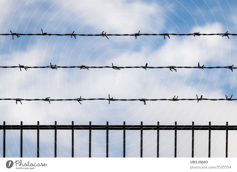 Barbed wire over a fence from fair weather clouds Wire fence Fence Clouds Beautiful weather cordoned off impermeable no passage cloudy Barrier wire