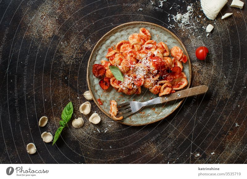South italian  pasta orecchiette with tomato sauce and cacioricotta cheese apulia tomatoes sugo top view dark basil green herbs leaves copy space wooden cooked
