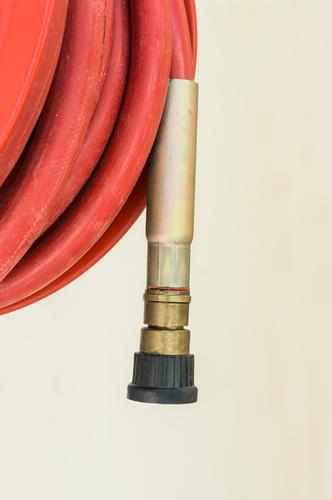 There the end of the fire hose hangs down, full of expectation for the next fire Fire hose Hose Fire fighting detail coiled Red Black Brass Metal Rubber Plastic