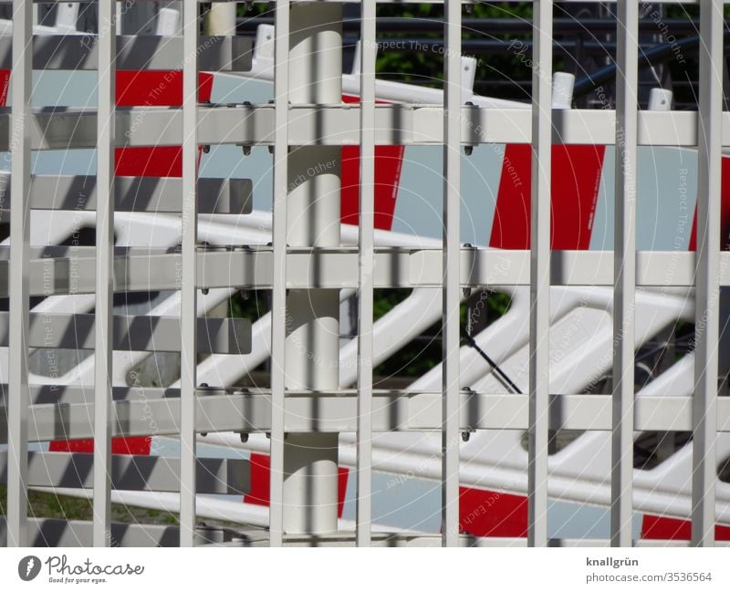 Red and white barriers behind a white metal fence cordon Barrier Protection Safety Fence Exterior shot Border Metal Structures and shapes Deserted Colour photo