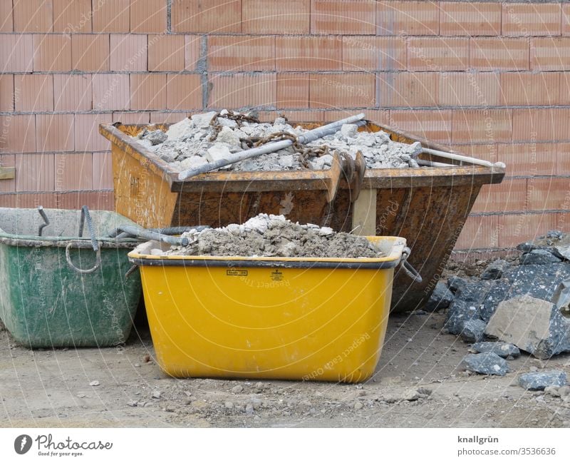 Three differently sized and differently coloured containers with building rubble on one construction site Construction site Building rubble