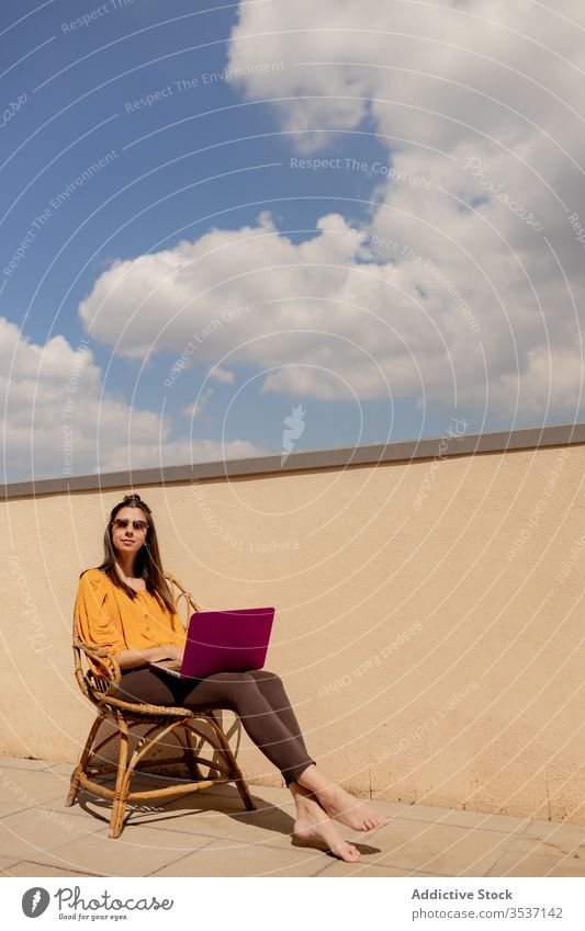 Young woman with laptop sitting on chair terrace home work using enjoy freelance quarantine lifestyle sunshine browsing female brunette casual outfit purple