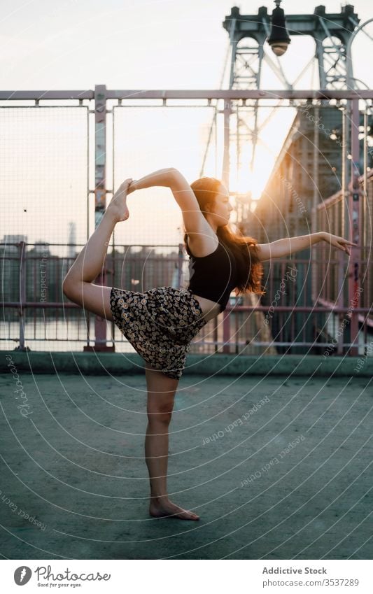 Tranquil woman doing yoga on bridge practice cityscape flexible asana lord of dance pose tranquil female urban scenery casual outfit skirt exercise natarajasana