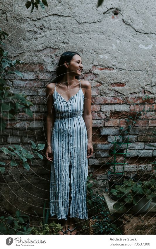 Young woman standing in a garden old pavement style dress rest female path plant relax serene tranquil peaceful harmony calm summer idyllic flora stripe elegant