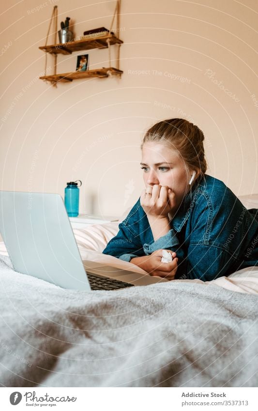 Woman watching movie while having hot drink and using laptop woman cry facial paper tears sad upset home bed displeased surfing lying down social media serious