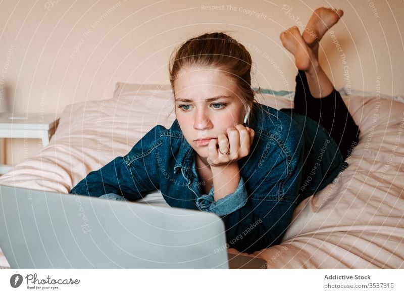 Woman watching movie on laptop in cozy bedroom woman home using lying down surfing social media listen female interest film earphones lounge wireless thoughtful