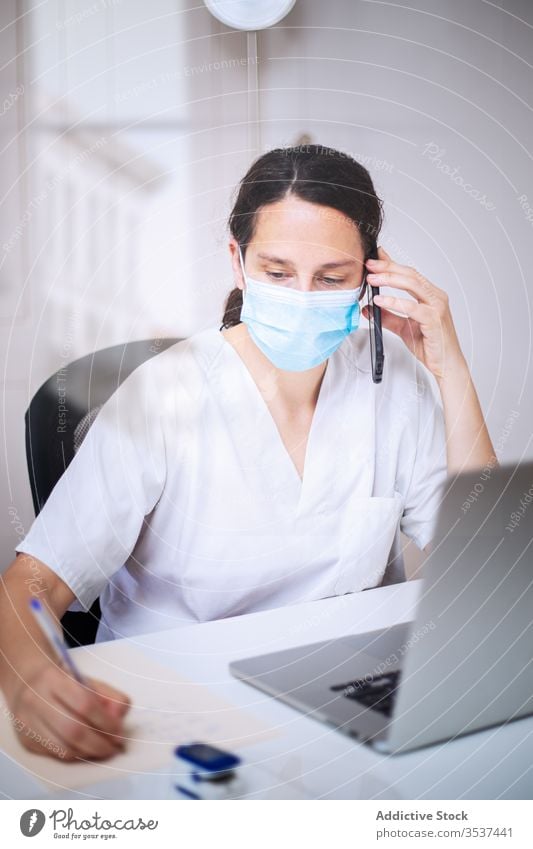 Young female doctor in medical mask working on laptop in clinic woman uniform glove desk serious hospital professional covid 19 coronavirus pandemic outbreak