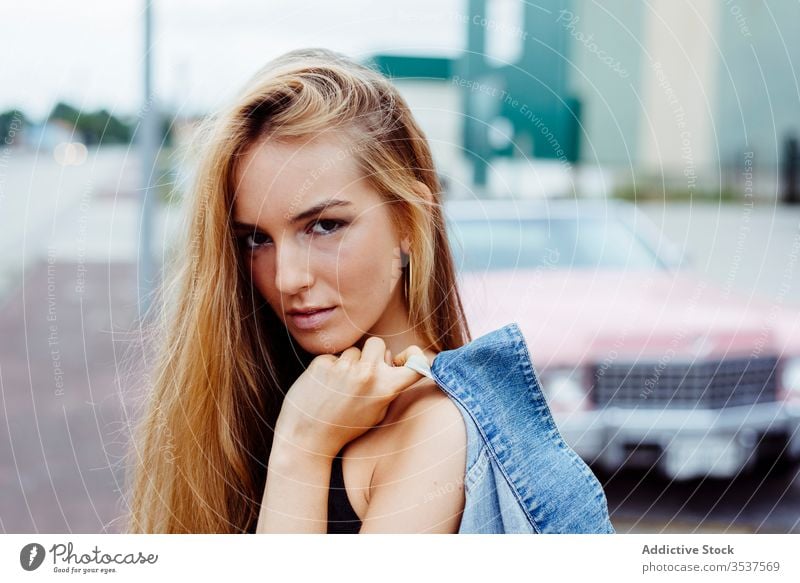 Sensual blonde girl portrait standing on the sidewalk looking at the camera woman young braids sitting pink car classic old grunge summer leisure urban city