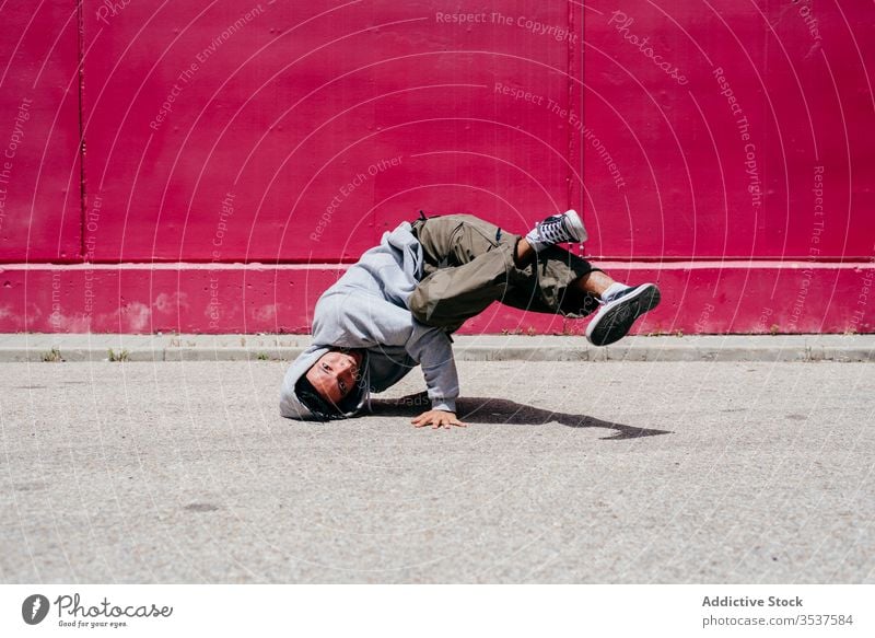 Young hispanic men doing acrobatics near to a pink wall on the street urban dance lifestyle city posing standing colorful daylight mixed hat hip-hop cool modern