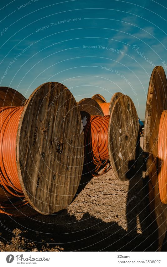 Rollen auf der Baustelle rollen spulen kabel kabeltrommel bauen baustelle sommer sonne himmel orange braun holz material baumaterial