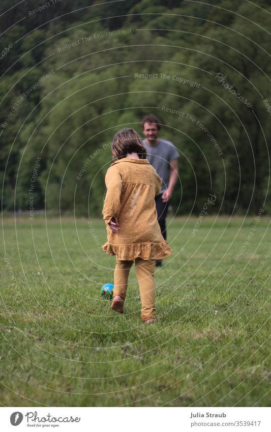 Child playing football with a man in a meadow Father girl soccer Meadow Places huts Forest Edge of the forest Dress Ball mustard yellow Playing Running move