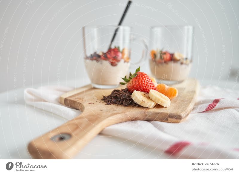 Cups of yoghurt with fruits cup breakfast morning dessert strawberry tangerine banana chocolate fresh delicious glass cutting board wooden food cream dairy