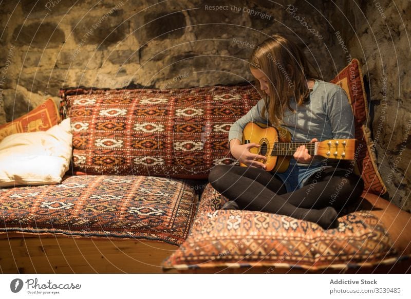 Girl playing ukulele on couch in stone house during vacation in Spain girl country practice sofa music comfort cozy cantabria spain relax leisure young enjoy