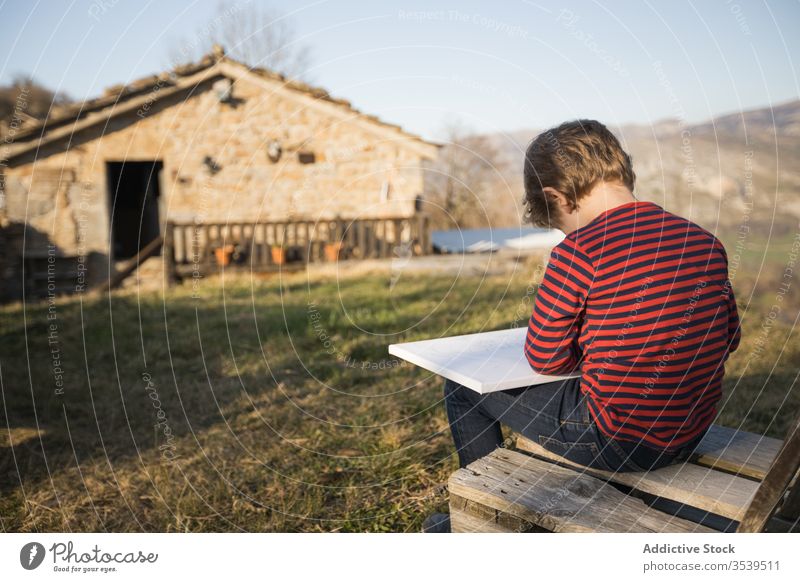 Boy drawing while sitting on bench in village in highlands boy canvas inspiration art paint mountain hobby child landscape magnificent weekend cantabria spain