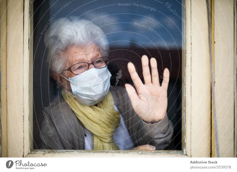 Senior woman in protective mask looking out window senior coronavirus home lonely anxious desperate unhappy sad quarantine prevent old female alone depression